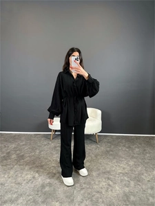 Détail du tissu plissé noir sur la chemise à manches bouffantes et le pantalon