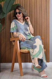 Detail of V-neck knit top and wide-leg trousers with blue-green camo print on a model