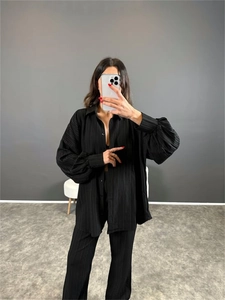 Détail de la chemise plissée noire et du pantalon assorti avec texture à manches bouffantes