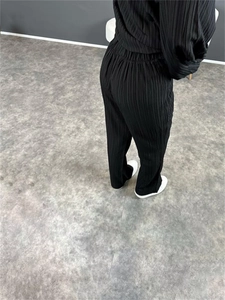 Détails de la texture plissée verticale sur la chemise noire à manches longues et le pantalon