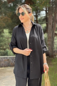 Detail view of a black long-sleeve button-down shirt paired with stylish casual pants
