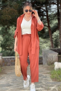 Detail of terracotta long-sleeved shirt and trousers set with a woven straw handbag