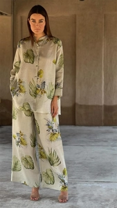 Detail of tropical green leaf print on a beige linen blend long sleeve shirt and pants set