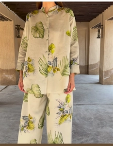Detail of tropical monstera leaf print on light grey linen shirt and trouser set