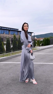 Detail of silk satin long sleeve grey dress with elegant pleated texture and fluid drape