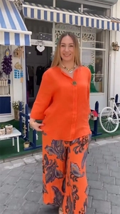 Détail de chemise en lin orange vif et pantalon large imprimé dans un style urbain chic
