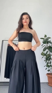 Detail of high waisted wide leg trousers and crop tube top in black fabric