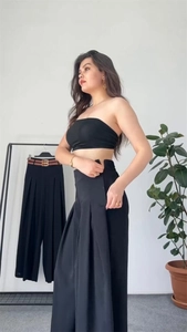 Detail of high waisted pleated wide leg trousers with a flowing black chiffon fabric texture