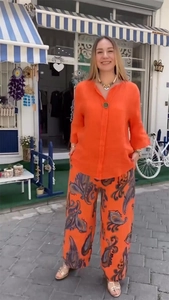 Détail de la chemise en lin orange vif et du pantalon large à motif paisley