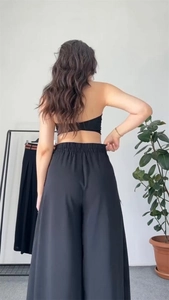 Rear view of black wide-leg trousers with an elastic high waist on a model