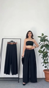 Detail of high waisted black wide leg pants with a brown belt and golden buckle