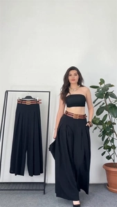 Detail of high-waist black wide-leg pants with brown leather belt and gold buckle