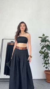 Chic black two-piece set featuring tube top, wide-leg trousers, and brown faux leather belt