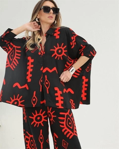 Detail of loose-fit shirt and wide-leg pants with red abstract pattern on black fabric