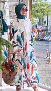 Detail of bohemian printed long cardigan and wide-leg trousers set with straw tote bag
