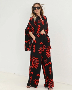 Detail of loose fit shirt and wide leg pants with red tribal print on black fabric