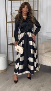 Détail d'un chemisier élégant en satin noir avec jupe rayée et nœud de ceinture à la taille