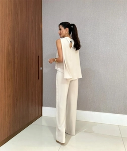 Detail view showing the draped cape back design of a beige sleeveless top and trousers