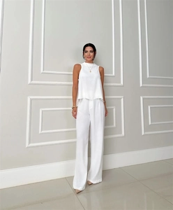 Detail view of white two-piece set featuring sleeveless high-neck top and wide-leg trousers