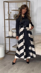 Détail d'une jupe trapèze rayée à taille haute avec ceinture à nœud noir et chemise en satin