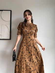 Detail of elegant satin dress with puff sleeves and vintage botanical print on bronze fabric