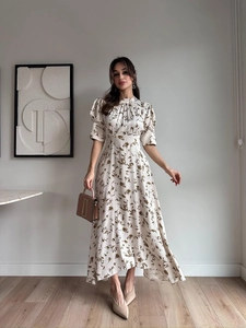 Detail of elegant white satin maxi dress with brown leaf print and puff sleeves