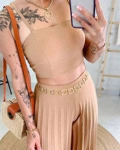 Detail of beige cropped camisole top and pleated wide leg pants with gold chain belt