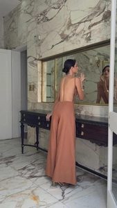Detail view of backless terracotta halter jumpsuit with high waist wide leg cut