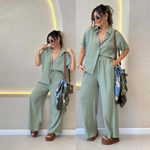 Detailed view of sage green pleated fabric texture on short sleeve shirt and wide pants