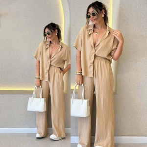 Detailed view of champagne pleated texture on loose-fit short sleeve shirt and wide-leg pants
