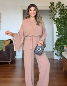 Detail of elegant rose pink long sleeve top with pearl cuffs and matching wide leg pants