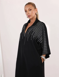 Detail of black dress featuring metal zipper neckline and white rhinestone line patterns