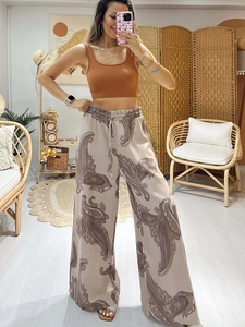 Detail of drawstring waist on beige paisley wide-leg trousers and brown ribbed crop top