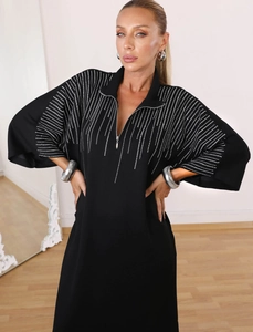Detail of black kaftan dress featuring a zip stand collar and silver rhinestone stripes