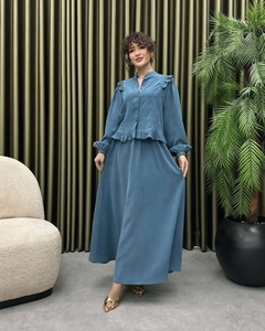 Detail of elegant dusty blue two-piece set with ruffled shirt and long flowing skirt