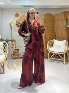 Detail of dark red paisley print on bohemian loose long sleeve shirt and wide leg trousers