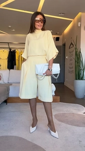 Détail d'un ensemble haut à manches chauve-souris jaune clair et short plissé