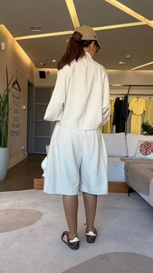 Détail d'un ensemble deux pièces blanc cassé avec veste chauve-souris et short taille haute
