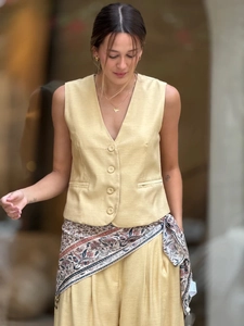 Détail du gilet en lin avec fermeture boutonnée, poches décoratives et foulard en soie