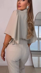 Detail of light beige elegant two-piece set featuring ruffle sleeves and high-waist pants