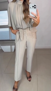 Detail of elegant two-piece set with high-neck top, straight trousers and hollow belt