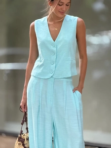 Détail de la texture d'un gilet en lin bleu clair et d'un pantalon large à taille haute