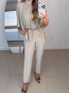 Elegant two-piece set featuring a beige high-neck sleeveless top and straight-leg trousers