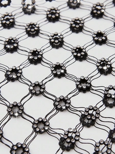Close-up of black fishnet mesh fabric with sparkling rhinestone flower embellishments