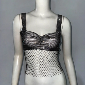 Détail d'un haut sexy en maille noire avec strass brillants et motif résille ajouré chic
