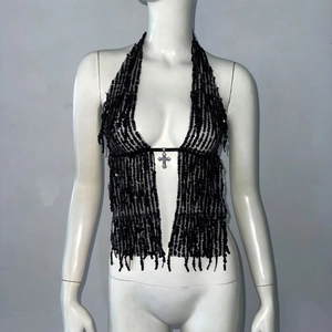 Détail du haut dos nu à paillettes noires avec croix argentée et ourlet à franges