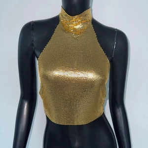 Macro shot of gold sequin crop top with metallic halter neck design for party