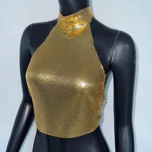Close-up of golden metallic sequin mesh fabric on a halter top for party festivals