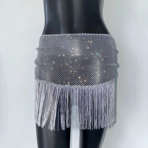 Détail de la mini-jupe argentée en maille avec franges en strass et pompons brillants