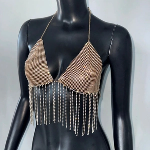 Detalle de top de bikini con flecos de pedrería dorada y cadenas para festivales